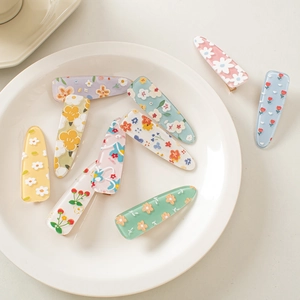 Detailed view of floral acrylic hair clips with daisy and strawberry patterns in pastel colors