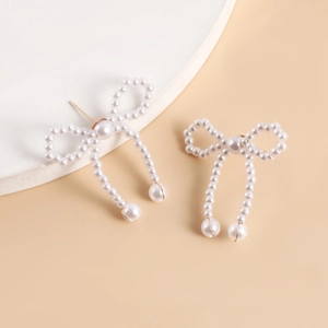 Close-up of handmade pearl bow earrings with elegant fringe tassels and gold studs