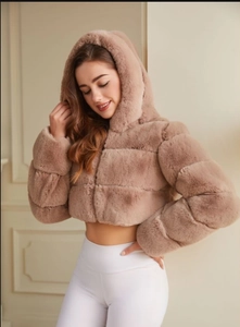 Close-up of fluffy faux fur texture on a dusty pink hooded jacket in a studio setting