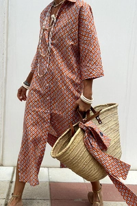 Detail of orange and blue geometric print shirt dress with woven straw basket bag