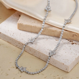 Detail of silver tennis necklace with sparkling floral charms and brilliant round cut stones