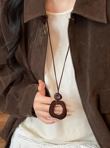 Detail of a minimalist dark brown resin pendant on a leather cord with velvet texture