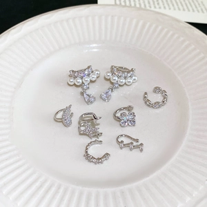 Flat lay of assorted silver zircon and pearl ear cuffs on a white ceramic plate