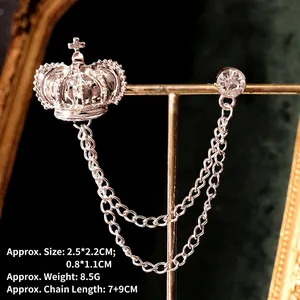 Detailed view of silver crown brooch with dual tassels and sparkling crystal on stand