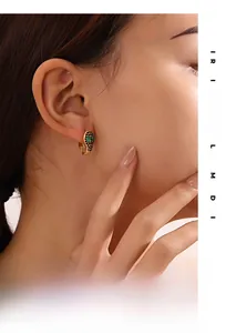 Gros plan d'une boucle d'oreille serpent avec pavé noir et yeux en pierre verte