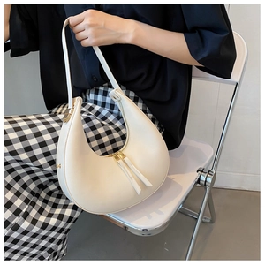 Close-up of a cream-colored crescent underarm bag with gold zipper and smooth leather texture
