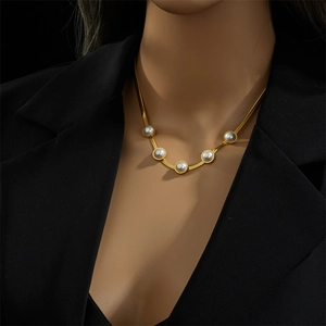 Elegante collana a serpente dorata con cinque perle su modella con un blazer nero