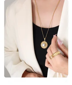 Detail of French vintage gold necklace with pearl pendant and striped wide ring