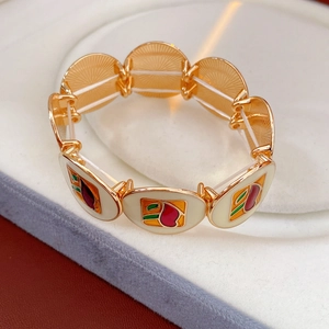 Detailed macro view of vintage gold-tone elastic bracelet showing colorful enamel patterns