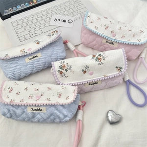 Detailed close-up of quilted floral pencil cases with macaron colors and heart charms
