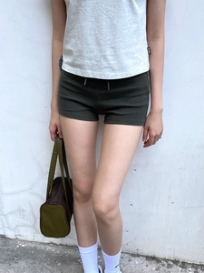 Slim fit olive green yoga shorts for women styled with a grey t-shirt and handbag