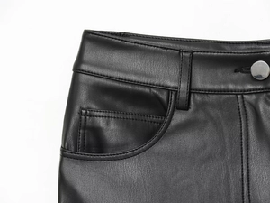 Detailed macro view of black faux leather texture with metal button and belt loops