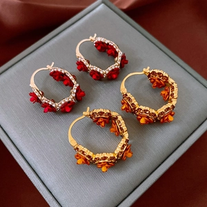 Détail de boucles d'oreilles en U dorées avec motifs floraux rouges et oranges