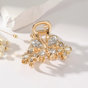 Detail of a gold butterfly hair claw with sparkling rhinestones on a stone base