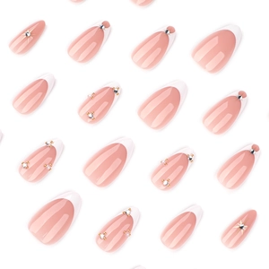 French tip press-on nails with white edges, rhinestones, and pearls on nude pink base