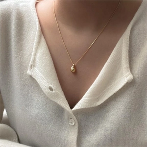 Minimalist gold teardrop pendant necklace in 925 sterling silver worn with white cardigan