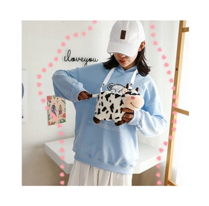 Detail of cute plush cow crossbody bag with black and white spots and white strap
