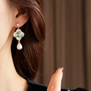 Gros plan de boucles d'oreilles vintage en émail avec perles et strass sur modèle