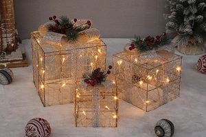 Close-up of lighted gold Christmas gift boxes with silver bows and festive pine cone details