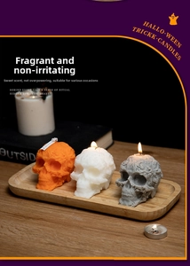 Detailed engraved skull scented candles in orange, white, and gray on a wooden tray