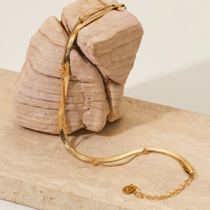 Golden double layer jewelry set with flat snake chain and beaded necklace on stone