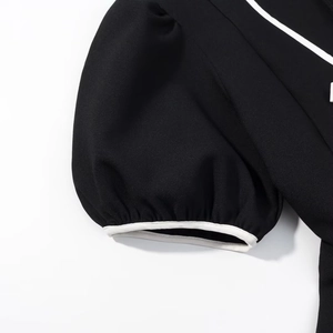 Détail des manches bouffantes noires avec liseré contrasté blanc sur une robe