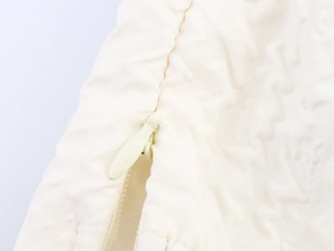 Détail macro d'une fermeture éclair invisible sur ensemble blanc gaufré élégant