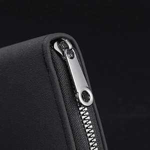 Close-up of black litchi pattern leather card holder with silver metal zipper detail