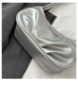 Détail du sac croissant argenté en cuir plissé avec étiquette de mode cousue et texture métal