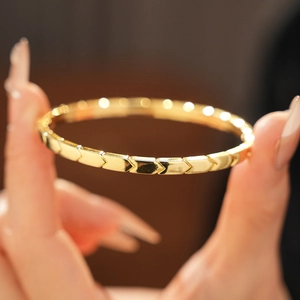 Close-up of golden geometric arrow-patterned bangle with polished finish and modern style