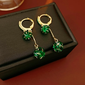 Macro shot of gold hoop earrings with green faceted crystal spheres on a jewelry box