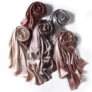 Detail of five glossy satin scarves rolled into roses in red, champagne, and rose pink