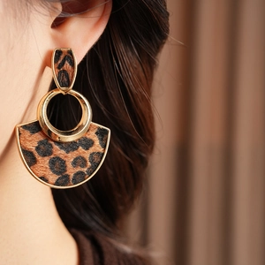 Model wearing leopard print fan-shaped earrings with gold trim and textured finish