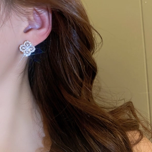Close-up of model wearing clover flower stud earrings with sparkling pavé zircon detail