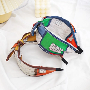 Detail of fabric knotted headbands with green and orange geometric silk patterns