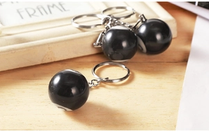 Close-up of resin number 8 pool ball keychains with metal chains on a wooden surface