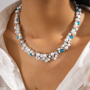 Detail of multilayer necklace with white pearls, blue beads and diamonds on neck