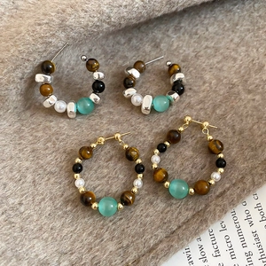 Detailed view of vintage hoop earrings with tiger eye stone and pearls on brown suede fabric