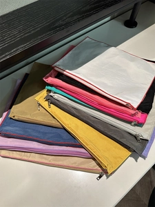 Stack of colorful nylon zipper pouches in various vibrant colors for organized storage
