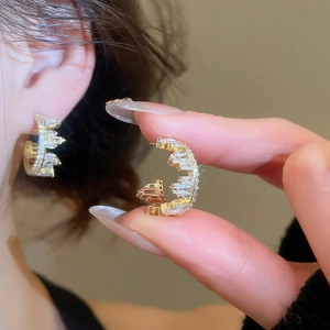 Macro shot of gold C-shaped earrings with micro-set white cubic zirconia stones