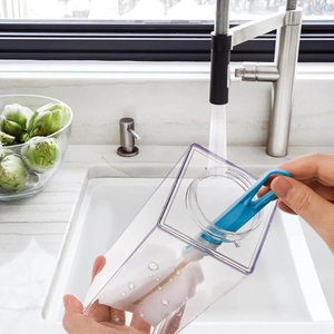 Detail showing a blue brush cleaning a 1000ml square plastic milk carton water bottle