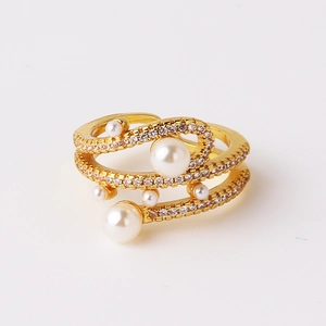 Detail of gold spiral ring with layered bands featuring white pearls and zircon pavé