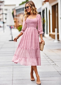 Detail of pink floral dress with smocked square neck and elegant tiered midi skirt