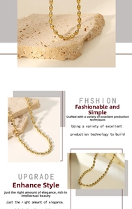 Detail of 18K gold plated stainless steel oval bead chain necklace on white silk fabric
