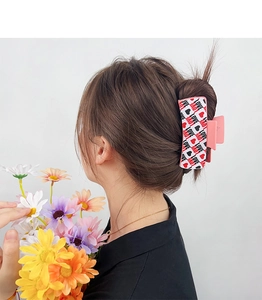 Detail shot of heart and LOVE patterned rectangular hair claw clip worn by a model