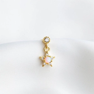 Macro shot of gold star earring featuring a pink opal center and sparkling cubic zirconia