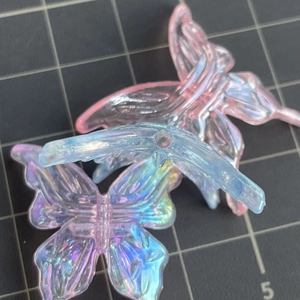 Macro shot of iridescent gradient butterfly charms with detailed texture on a cutting mat