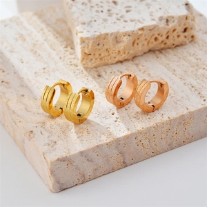 Minimalist double-line frosted gold and rose gold hoop earrings on beige stone