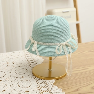 Detail of mint green straw hat with white lace trim and bow for girls' summer sun protection