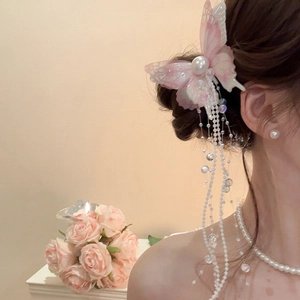Detailed close-up of butterfly hair clip with pink gradient mesh and long pearl tassels